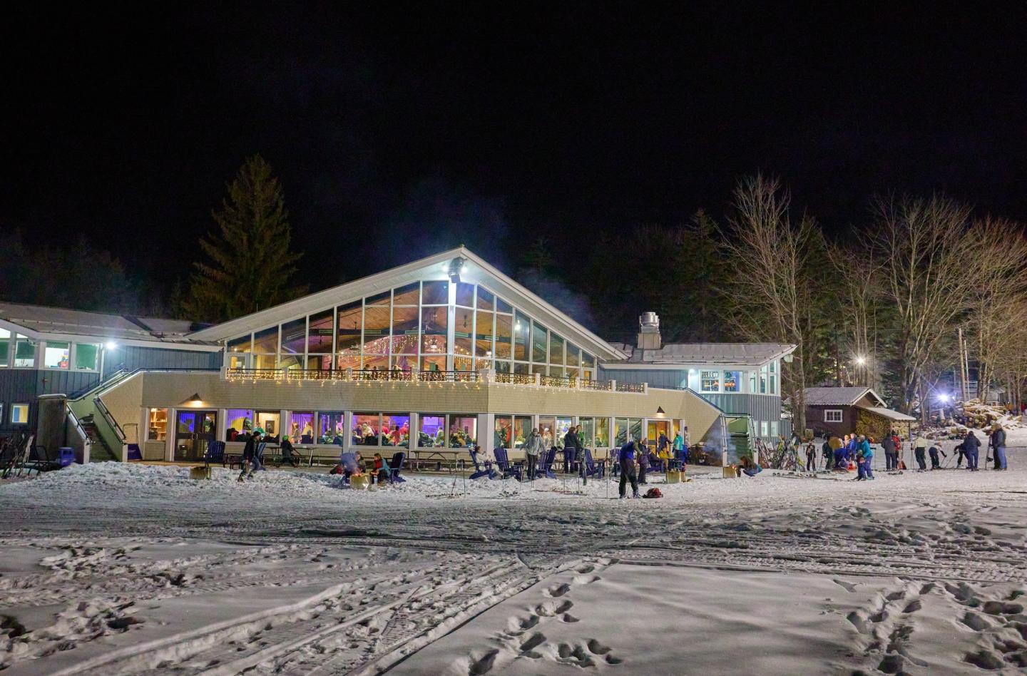 Middlebury Snowbowl in USA: a group of people standing outside of a building at night.