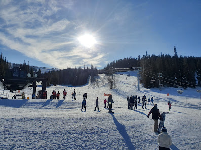 Winter scene at Pomerelle in Albion, Idaho, highlighting a bustling ski resort dotted with chalets, ski lifts, and people enjoying winter sports activities.