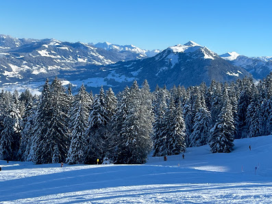 Winter scene at Bödele ski resort in Austria, showcasing snow-covered slopes, a charming chalet, and people engaging in winter sports activities.