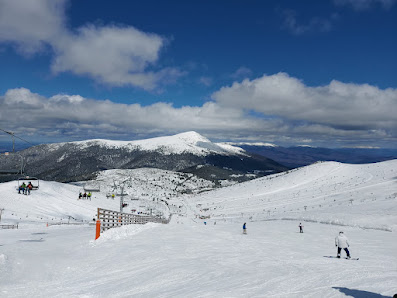 A ski resort in Valdesquí, Madrid, showcasing people enjoying winter sports on snow-covered slopes. A charming chalet is nestled amidst the splendid winter scenery.
