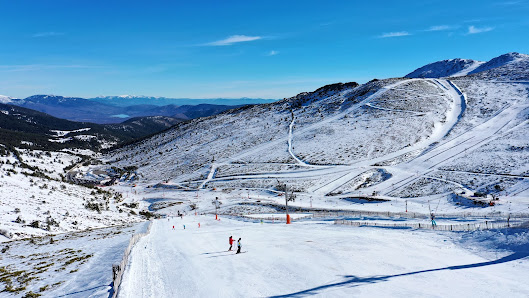 Winter scene at Valdesquí ski resort in Madrid, Spain. Skiers enjoying winter sports amidst stunning snowy landscapes with a chalet in the background.
