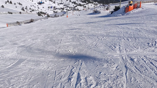 A skier gliding down the dazzling snow-covered slope of Valdesquí resort in Madrid, Spain. The charming chalet and an overhead ski lift add to the picturesque winter sports scene.