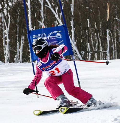 A skier descending the snowy slopes of Monte Catria in Pesaro-Urbino, Caprile, Marche, Italy. The atmosphere of a bustling winter sports scene is evident.
