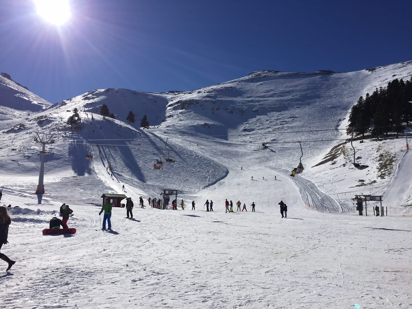 Winter sports enthusiasts enjoy the snow-covered slopes at Ski Center in Chelmos, Kalavrita, Greece. A chalet nestled in the scenic landscape serves as a cozy resort amidst the skiing paradise.