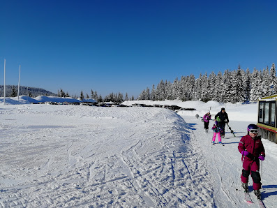 Winter sports scene at Sjusjøen in Lillehammer, Norway, showing a bustling ski resort, a quaint challet, and a family enjoying skiing.