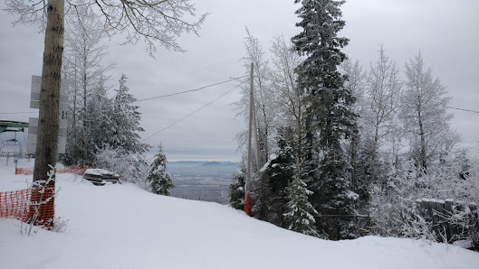 Winter scene at Tabor Mountain featuring a ski lift and skiers enjoying the slopes at a ski resort, with a charming chalet in the backdrop in Prince George, British Columbia, Canada.