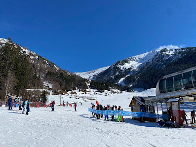 Winter sports scene at Ascou Pailhères in Ariège, France: showing a lively ski resort with skiers heading up the mountain on a ski lift, surrounded by cozy chalets.