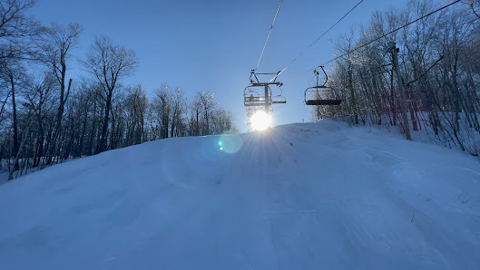 A picturesque scene at Sommet Morin Heights ski resort in Quebec Canada featuring a ski lift a skier making their way down snow-covered slopes