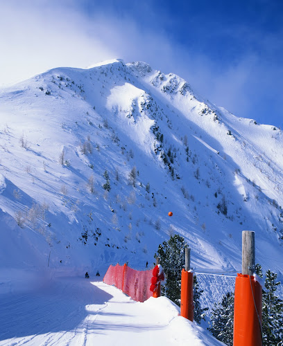 Winter sports enthusiasts skiing at the Champex-Lac ski resort in Switzerland. The mountain and snow-covered slopes provide a picturesque backdrop.