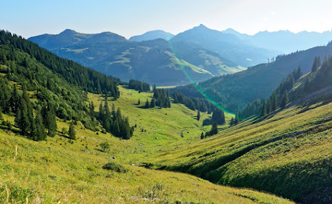 Austrian chalet nestled at the foot of a mountain in Schattwald-Zöblen, Tyrol. The ski resort is basking in a sunny day's glow, with a solitary mountain bike hinting at the area's active lifestyle.