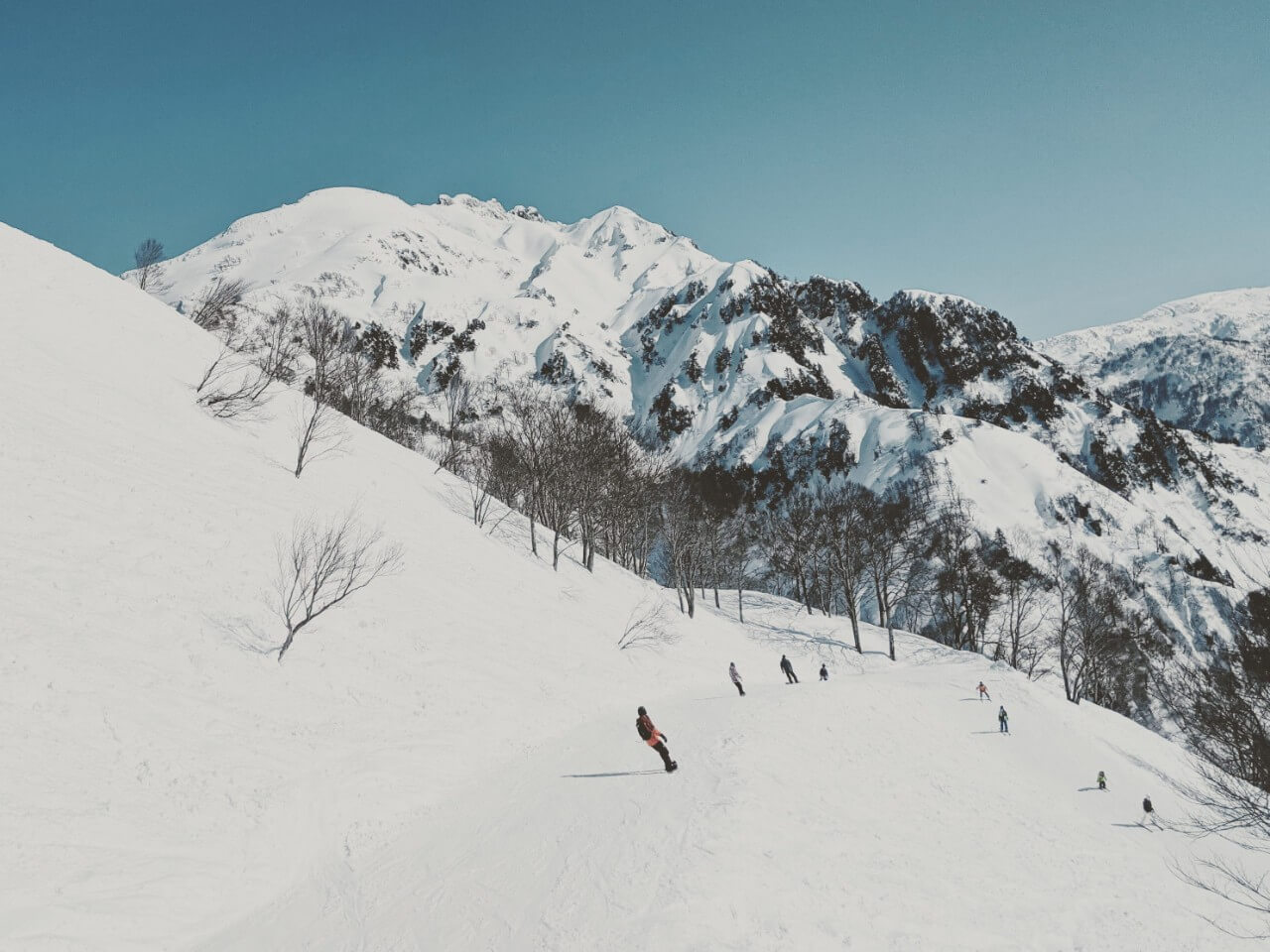 Muikamachi Hakkaisan in Japan - a group of people skiing down a snow covered mountain.