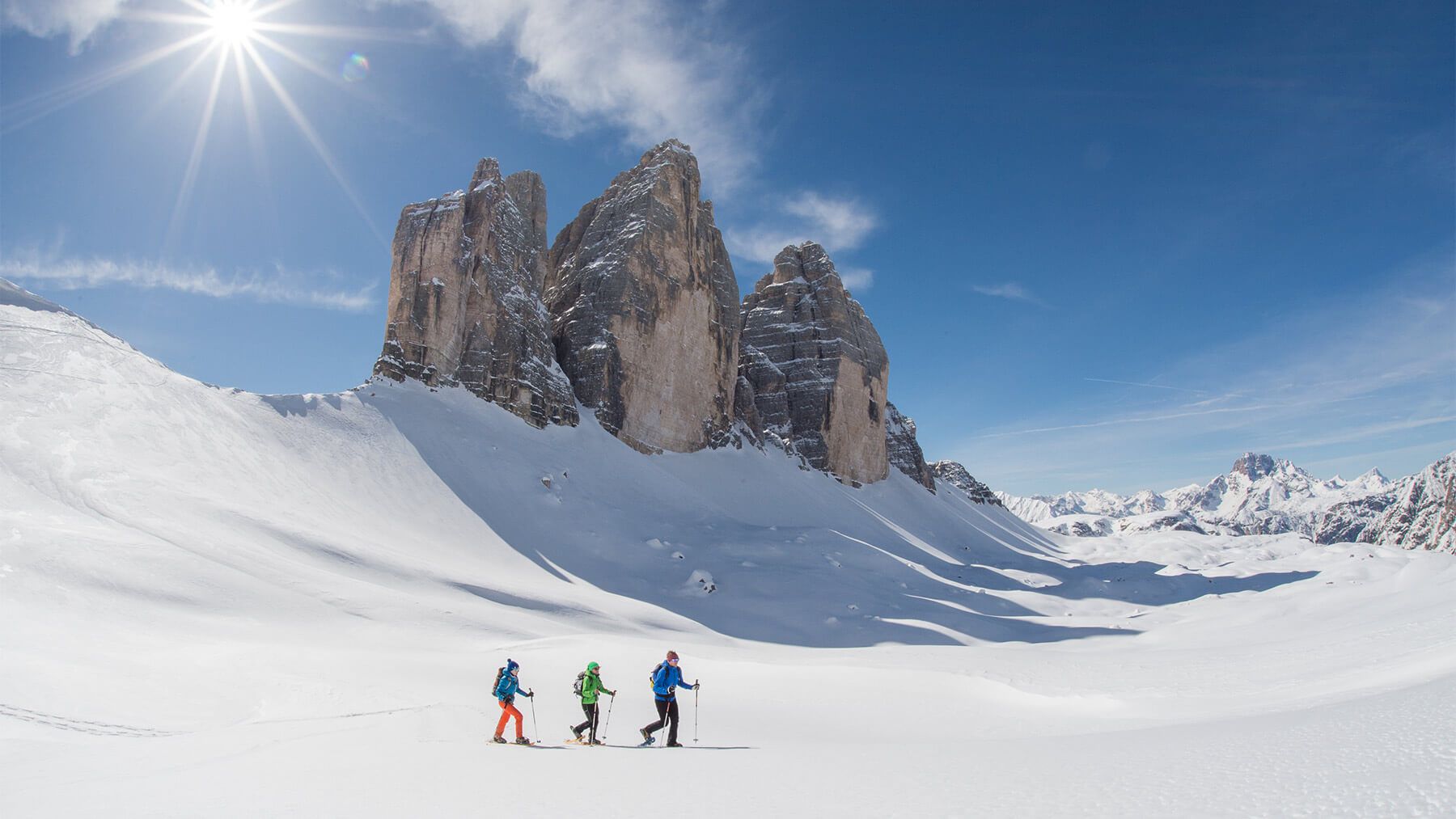 Three Peaks Dolomites in Italy - two people skiing down a snow covered mountain.