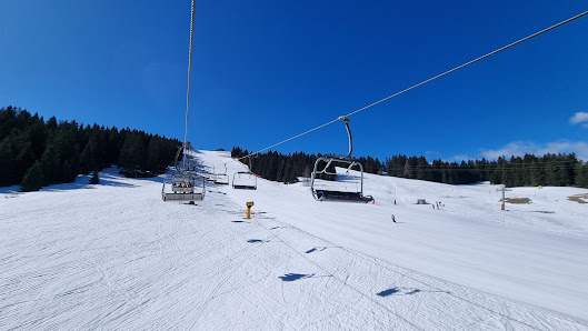 A beautiful winter scene at Borno - Monte Altissimo ski resort in Italy showcasing a ski lift a bustling winter sports centre and a charming chalet nestled in the snow-covered landscape.