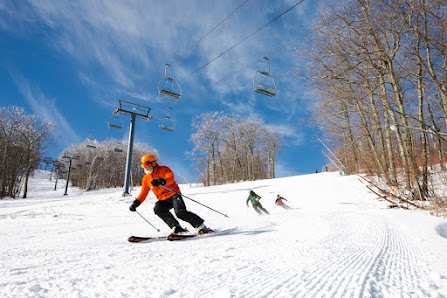 A skier takes to the snowy slopes at Catamount Ski Resort in Hillsdale New York gliding past the bustling ski lift. The winter sports scene is vibrant in the tranquil Hudson Valley.