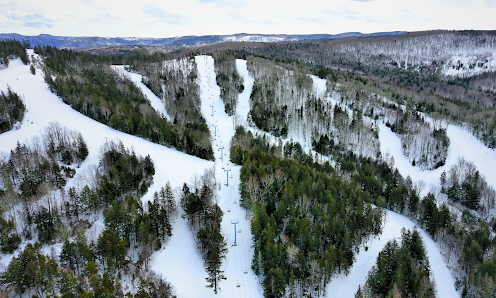 Ski resort at Poley Mountain in Canada featuring a wintery scene with a ski lift, snow-covered slopes, skiers enjoying winter sports.