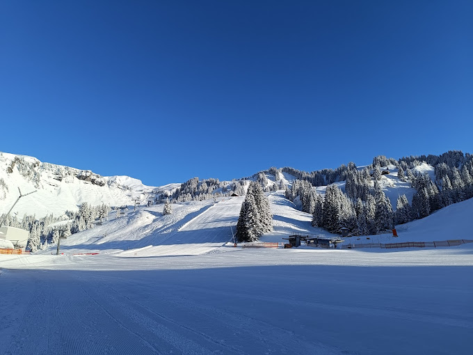 Damüls Mellau in Austria - a snow covered ski slope with trees in the background.