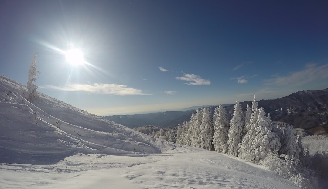 A picturesque winter scene at Doganaccia 2000 in Cutigliano, Tuscany, featuring a lively ski resort nestled in gorgeous snow-covered mountains.