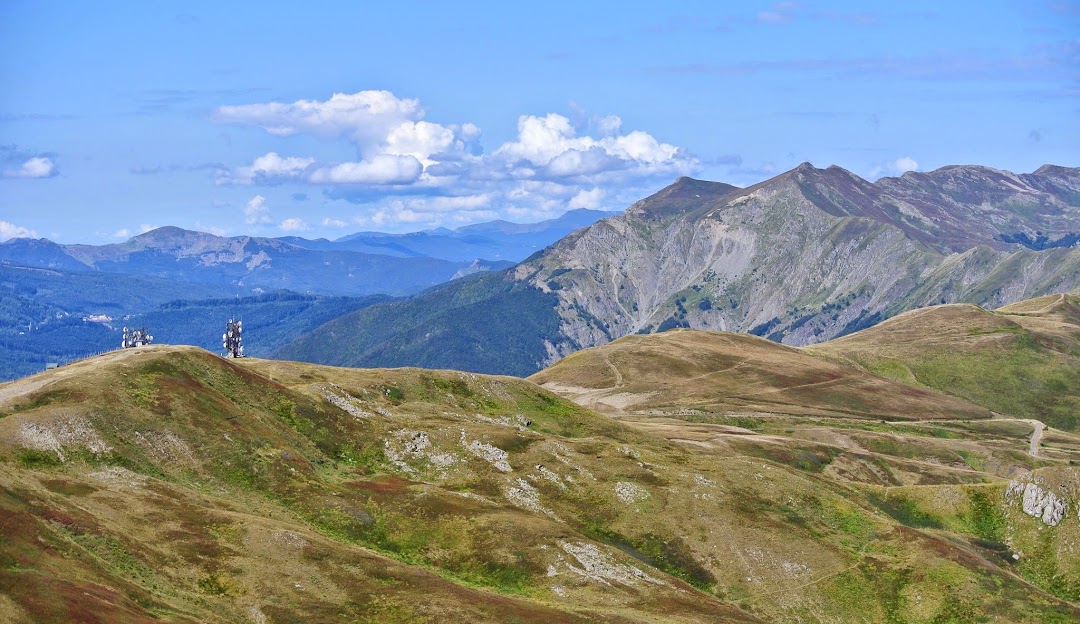 A picturesque view at Doganaccia 2000 in Tuscany Italy featuring a charming chalet nestled among mountains. Notable elements include a ski resort and ski lift enhancing the winter haven ambiance.
