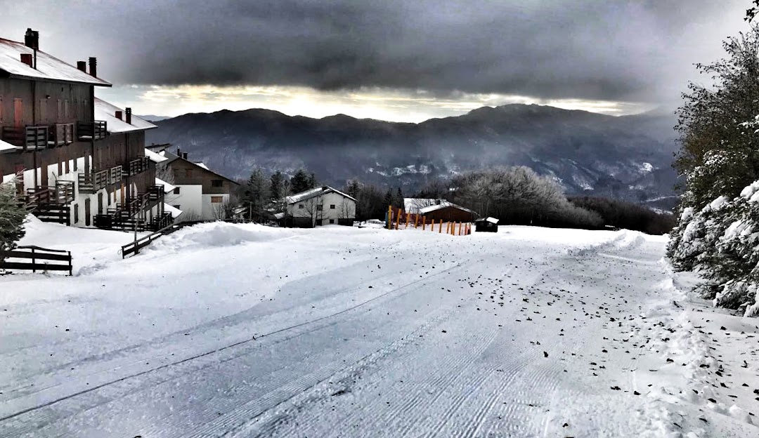 A charming chalet nestled amidst the stunning winter scenery at the Doganaccia 2000 ski resort in Cutigliano, Tuscany. Winter sports enthusiasts enjoy the snowy slopes.
