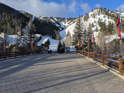 Winter sports enthusiasts enjoy a day on the slopes at Dollar Mountain – a ski resort in Sun Valley, Ketchum, Idaho, accentuated by stunning winter scenery and a distant ski lift.