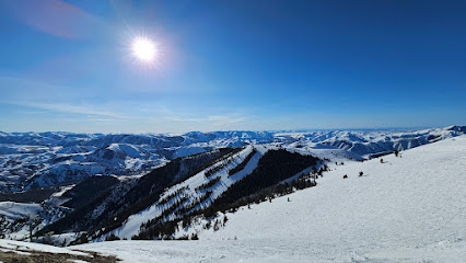 A skier explores Dollar Mountain in Sun Valley Idaho surrounded by the breathtaking beauty of the snow-covered slopes and ski resort nestled in the backdrop of the majestic mountain.