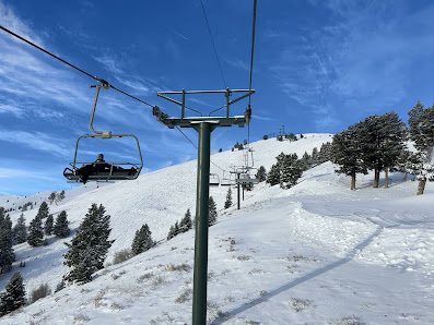 Ski lift ascending Dollar Mountain in Sun Valley, Idaho, amidst a winter landscape; skiers enjoying the snow-covered terrain at the ski resort.