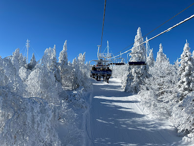 A striking winter scene at Mont Comi ski resort in Quebec Canada. A ski lift ascends a snowy slope against the backdrop of a serene picturesque