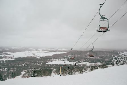 Winter scene at Mont Comi in Quebec, Canada, featuring skiers enjoying the slopes, a ski lift servicing the mountain, and stunning snowy surroundings.