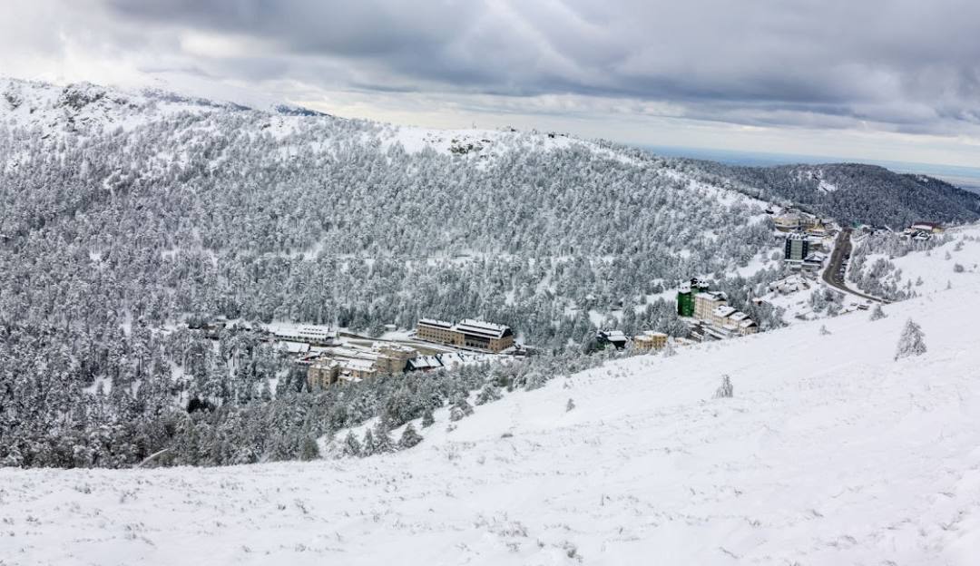 A scenic view of the Puerto Navacerrada ski resort in Madrid, Spain featuring a charming chalet, vibrant winter sports activities against the backdrop of a stunning winter landscape.