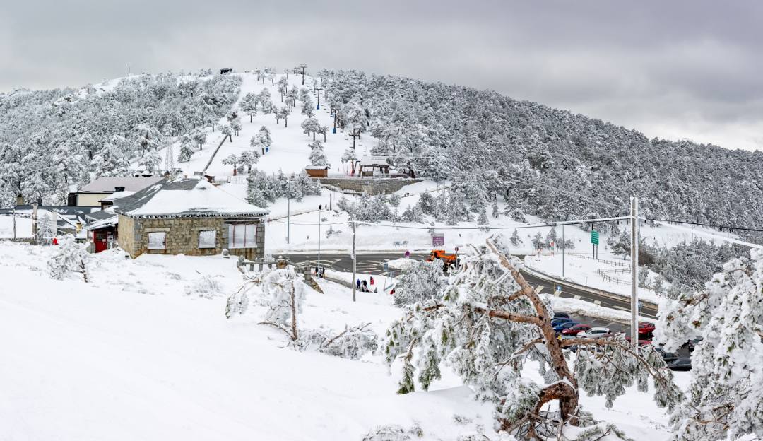 Skiing scene at Puerto Navacerrada, a winter sports centre in Cercedilla, Madrid, showcasing breathtaking winter landscape, vibrant ski resort, and operational ski lift.
