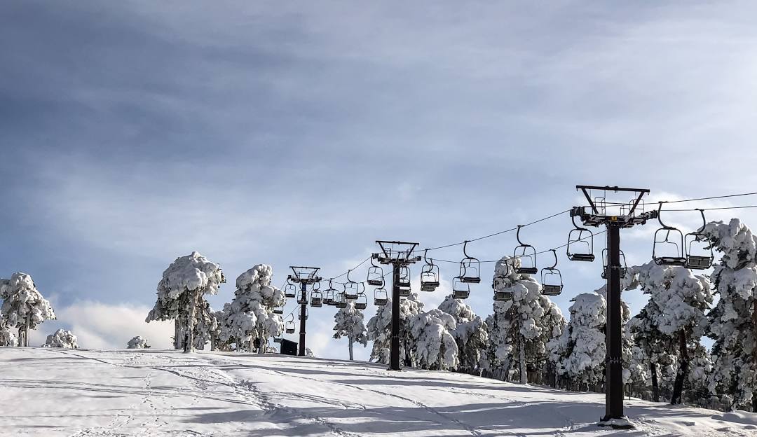 Winter scene at Puerto Navacerrada ski resort, Madrid, featuring a ski lift, skier, and stunning snowy landscape.