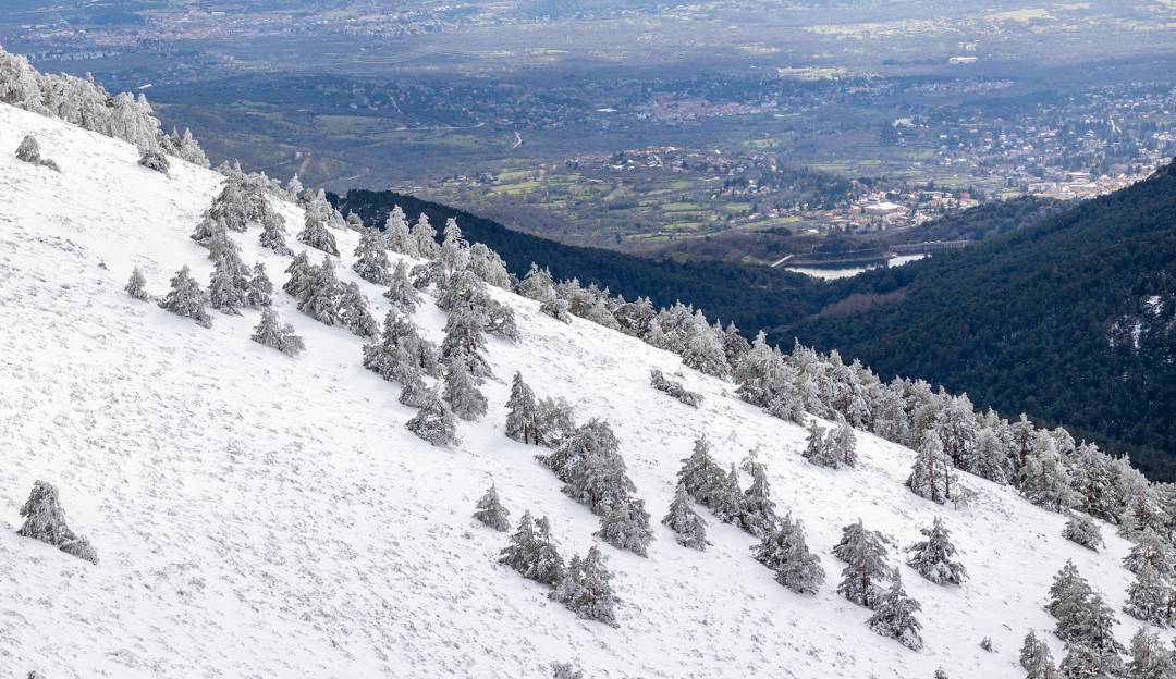Winter scene at Puerto Navacerrada, Madrid with snow-covered slopes, showcasing an active winter sport activity taking place at a scenic ski resort.
