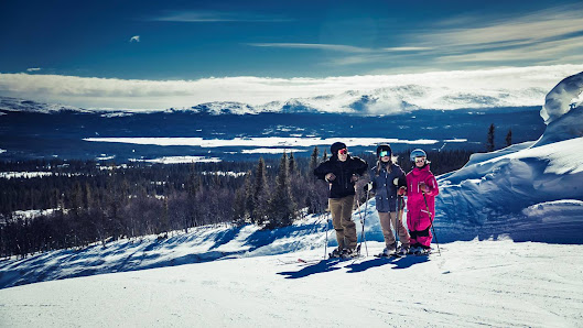 A family enjoying a day of skiing at Trillevallen ski resort in Northern Sweden surrounded by wintry scenery. There's a great sense of enjoyment of winter sports among the group.