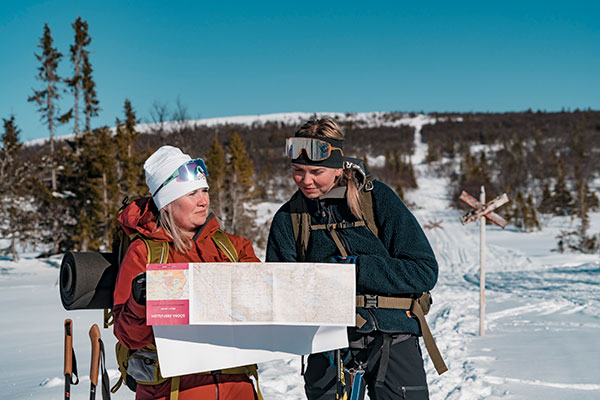 A skier and a family enjoying winter sports at the Trillevallen ski resort in Northern Sweden, with a charming chalet nestled in the snowy landscape.