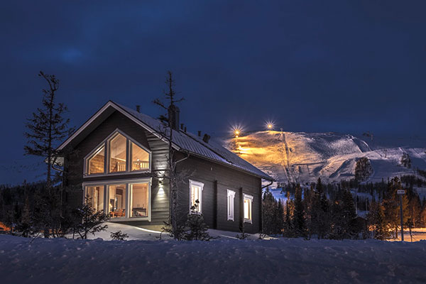 An enchanting view of Trillevallen, Sweden, spotlighting a lodge and mountain hut within a ski resort, showcasing a serene winter sports scene amidst stunning winter scenery.