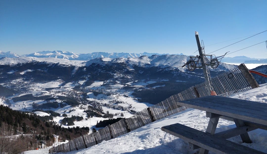 A picturesque scene at Gresse en Vercors ski resort in France depicting a ski lift ascending the snowy mountain a cozy chalet in the backdrop and a skier enjoying the winter sports.