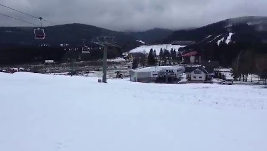 Ski resort in Bonera Ski areál Ramzová in the Olomouc Region; skier enjoying the snowy slopes; ski lift in use; picturesque winter scenery in the background.