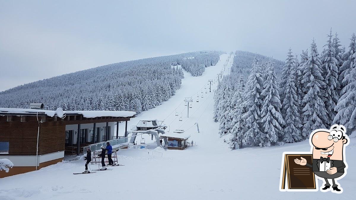 Bonera Ski areál Ramzová in Czech Republic - a ski slope covered in snow with people skiing down it.