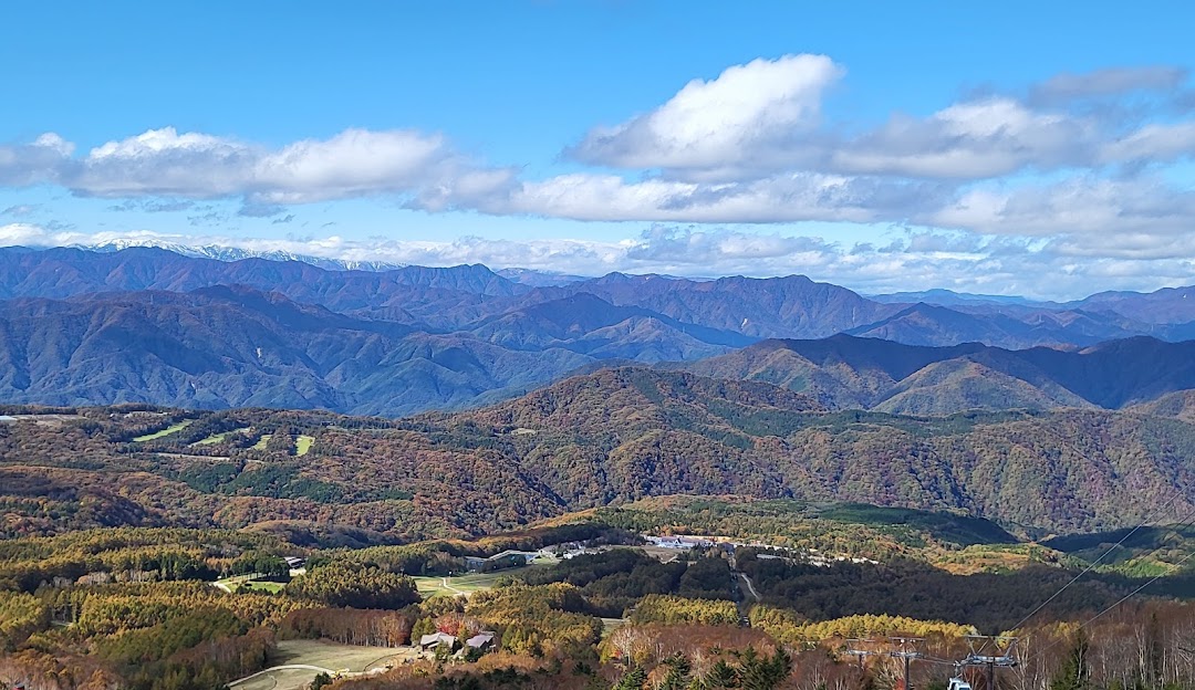 A winter scene at Hunter Mountain Shiobara in Japan, featuring a snow-covered mountain, a charming chalet, and individuals partaking in winter sports.