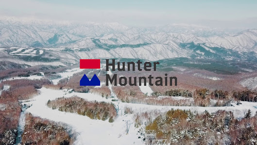 View of Hunter Mountain Shiobara in Japan, showcasing a stunning winter landscape. The scene includes a snowy mountain, a ski resort, and various winter sports activities.