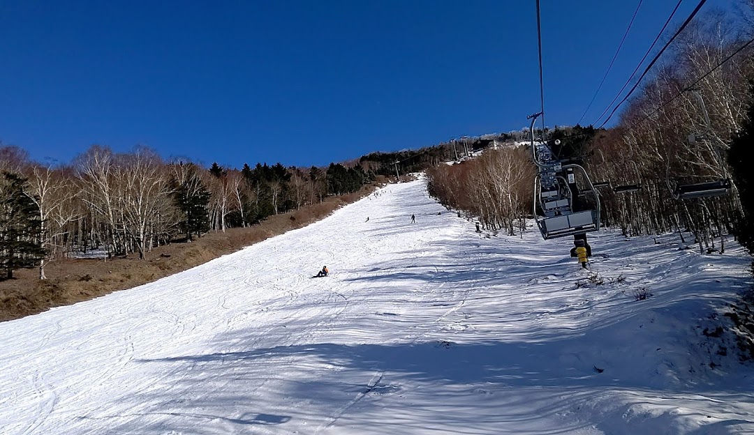 A winter sports scene at Hunter Mountain Shiobara ski resort in Japan featuring a ski lift transporting skiers up the snow-covered slopes.