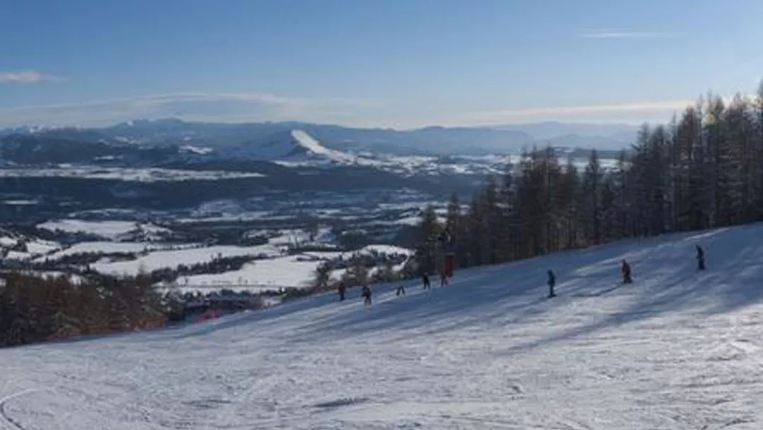 Winter scene at Chaillol ski resort in France; multiple elements including sports enthusiasts skillfully navigating snowy slopes indicate activity. A picturesque chalet, typical of the area, is also visible.