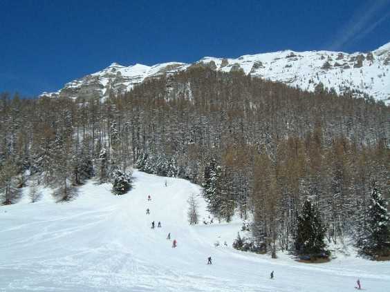 A picturesque image showcasing a lively skiing day at Chaillol ski resort in France. Skiers glide down the slopes visible chalet nearby and a ski lift in action.