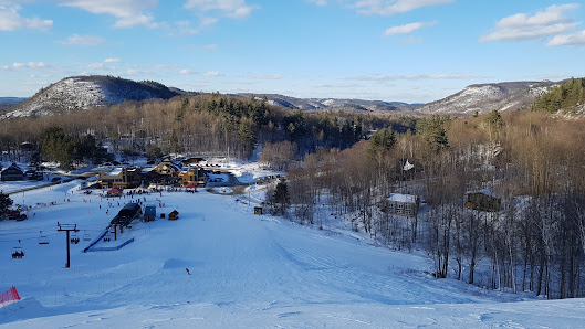 Winter scene at Mont Ste-Marie in Quebec, Canada, featuring a bustling ski resort, a ski lift in the distance, and skiers enjoying the snow-covered slopes.