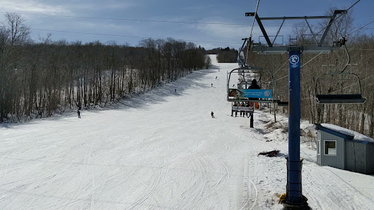 Winter sports enthusiasts enjoying the day at Crabbe Mountain ski resort in New Brunswick, Canada. The ski lift shuttles skiers up the snow-covered slopes.