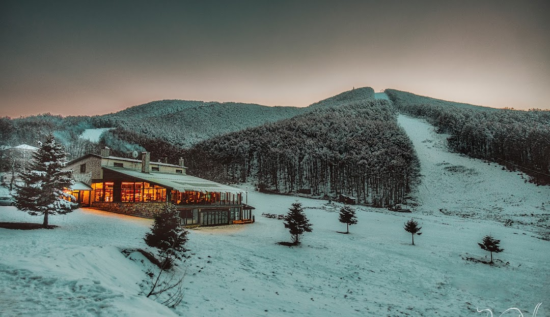 Winter scene at Vigla Pisoderi, Greece featuring a stunning snow-covered landscape, ski resort, and lodge amid a lively winter sports scenery.