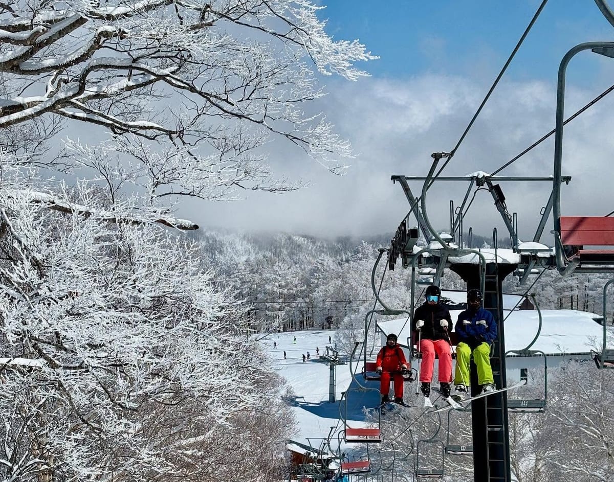 Tengendai in Japan - two people on a ski lift in the snow.