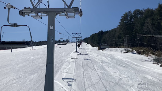 Ski lift in operation at Hida Funayama Snow Resort Arkopia in Japan, with a skier gliding down a snowy slope. Winter sports scene set against a cosy chalet.