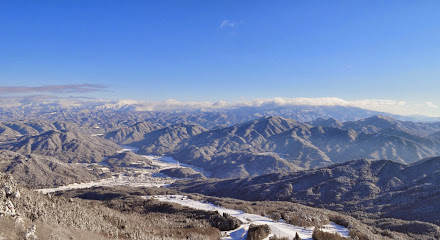 Winter panorama at Hida Funayama Snow Resort Arkopia in Japan, featuring snow-covered landscape with skiers enjoying the slopes and a charming chalet in the background.