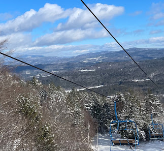 Ski lift ascending up snowy Tenney Mountain at a New Hampshire ski resort; skiers enjoying winter sports activities amid stunning winter scenery.